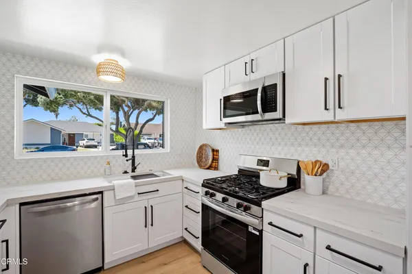 a kitchen with stainless steel appliances white cabinets and a stove top oven
