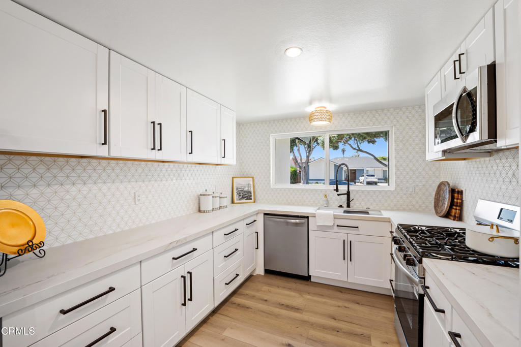 930 Topsail Court Oxnard, CA 93035 - Photo 4 of 31 a kitchen with stainless steel appliances granite countertop a sink stove oven and white cabinets with wooden floor