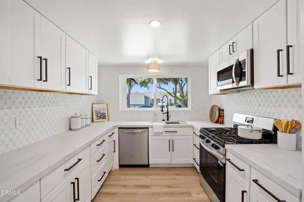 a kitchen with stainless steel appliances a sink stove top oven and cabinets