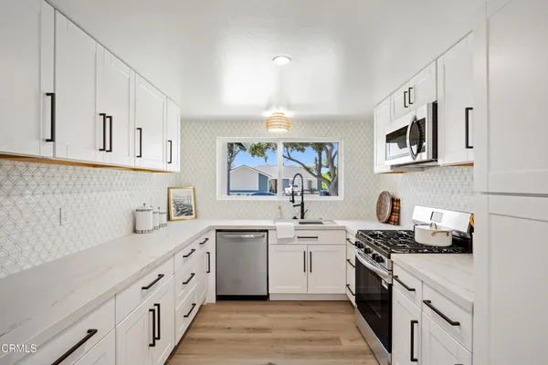 a kitchen with cabinets stainless steel appliances a sink and a window