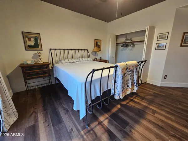 a bedroom with a bed next to a window with wooden floor