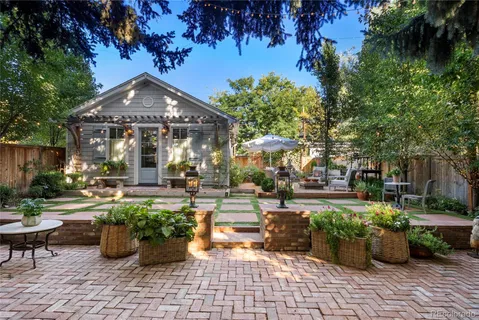 a view of a patio with table and chairs potted plants and a large tree