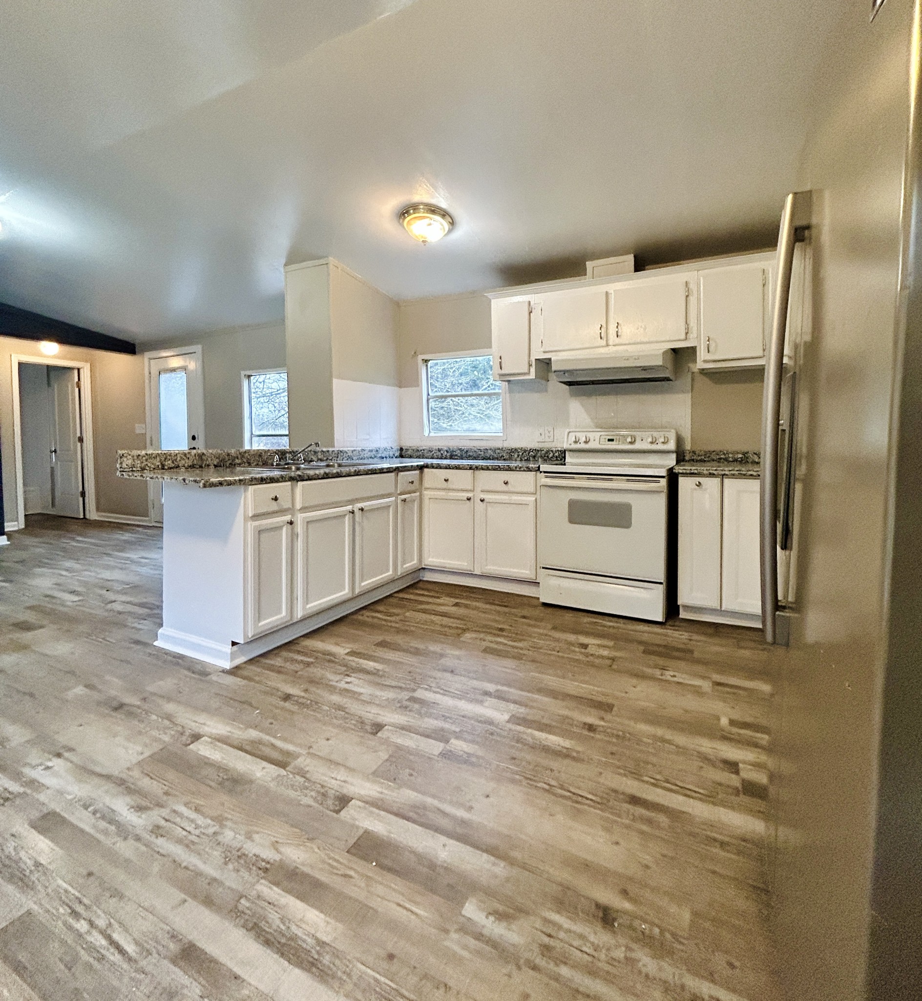 789 Riddle Lane Estill Springs, TN 37330 - Photo 4 of 11 a large kitchen with granite countertop a stove top oven a sink dishwasher a refrigerator and white cabinets with wooden floor