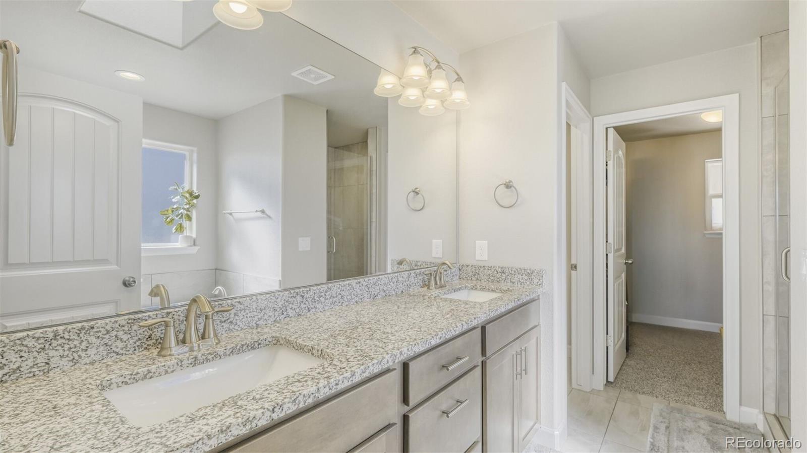 9093 Peaceful Valley Road Colorado Springs, CO 80925 - Photo 20 of 42 a bathroom with a granite countertop double vanity sink and a mirror