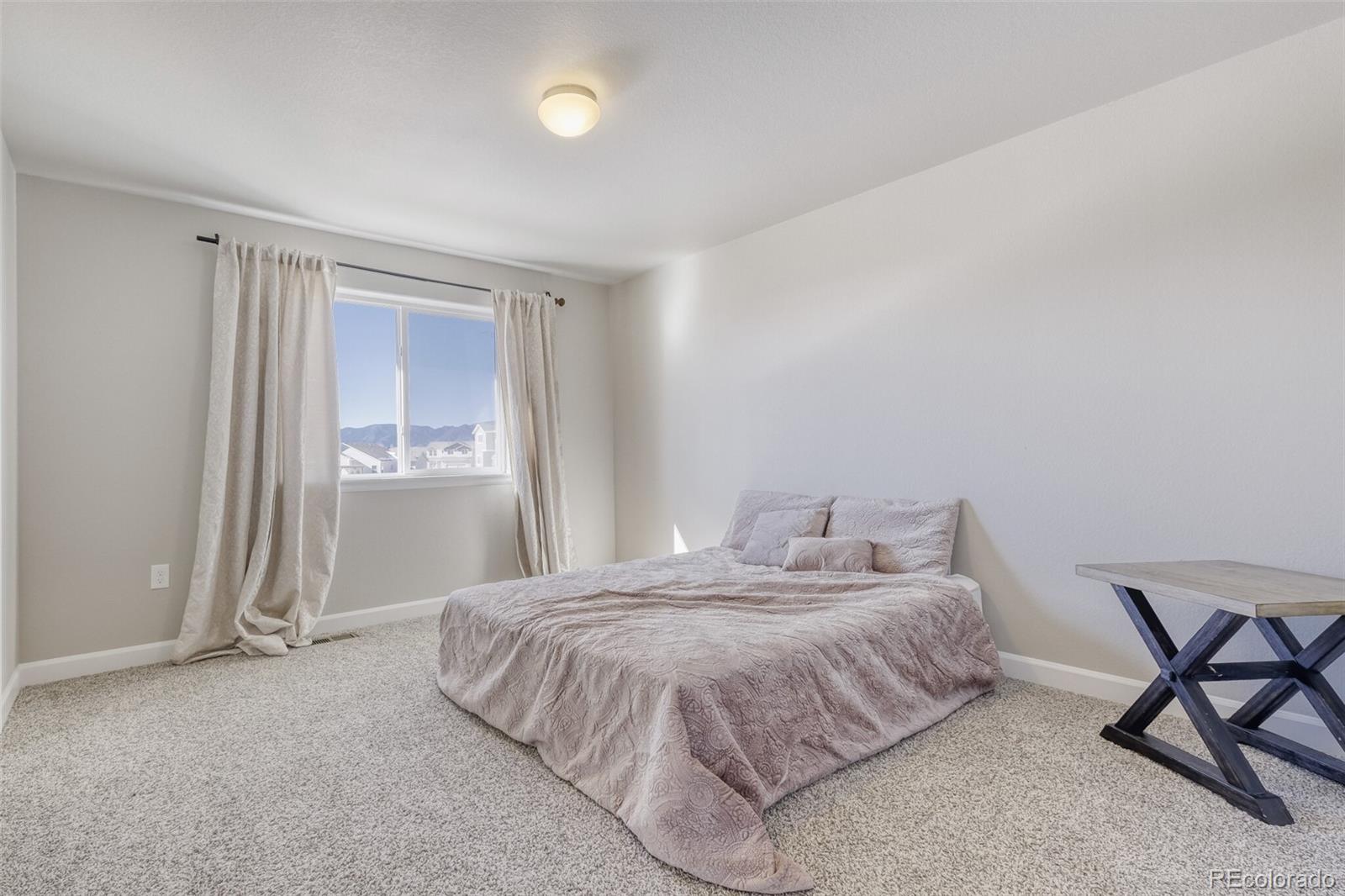 9093 Peaceful Valley Road Colorado Springs, CO 80925 - Photo 23 of 42 a bedroom with a bed and chair