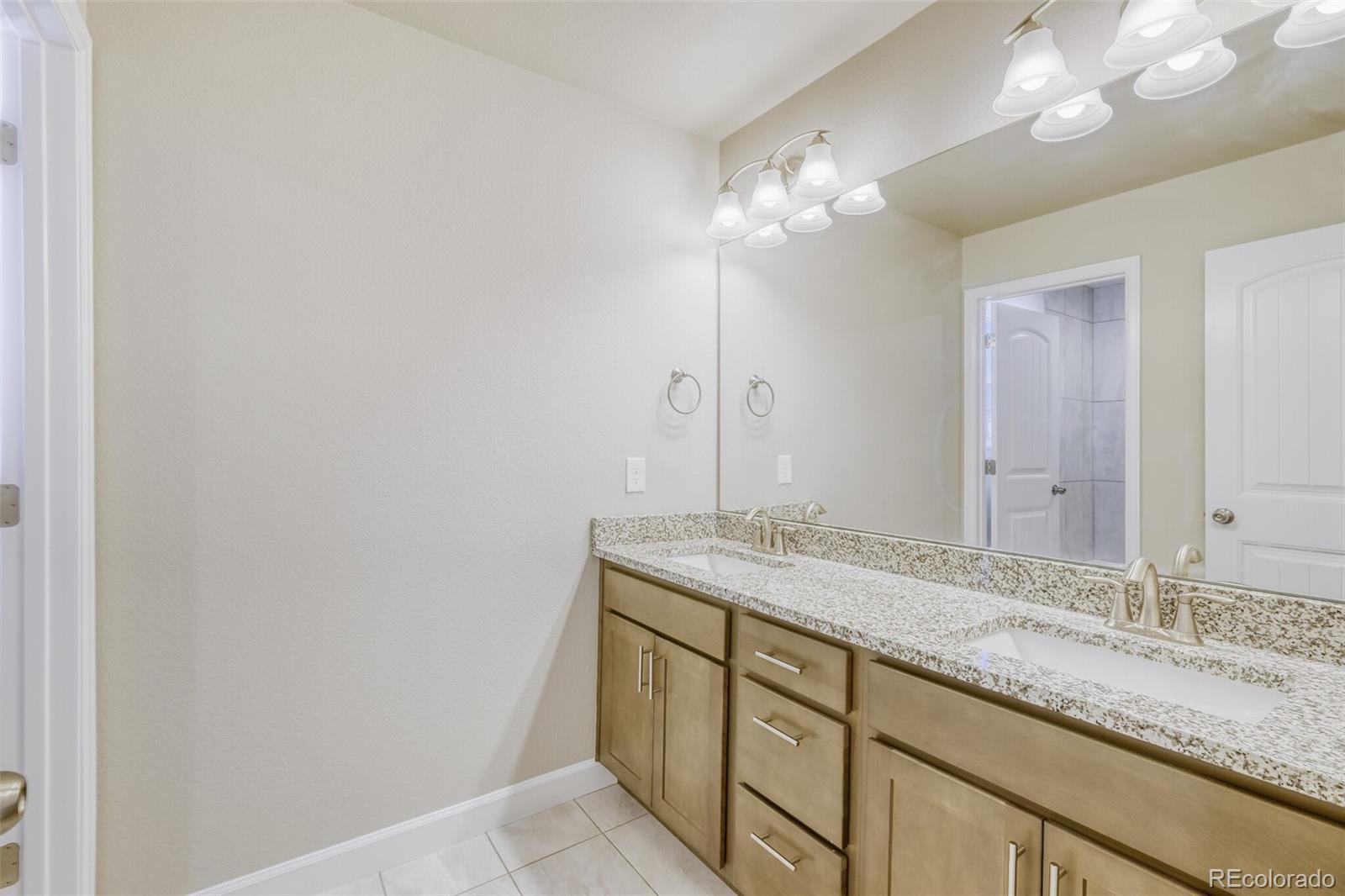 9093 Peaceful Valley Road Colorado Springs, CO 80925 - Photo 29 of 42 a bathroom with a granite countertop double vanity and a mirror