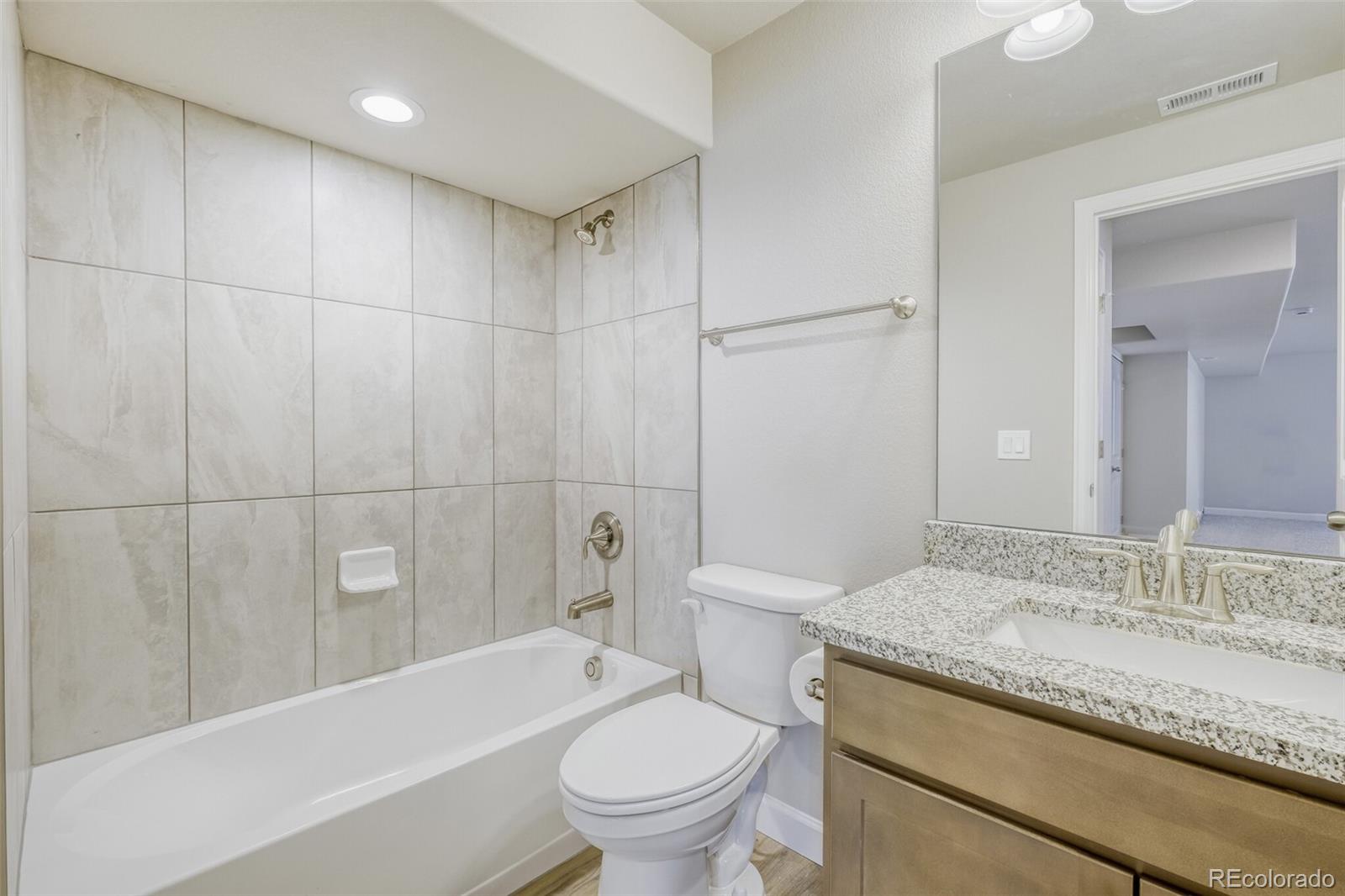 9093 Peaceful Valley Road Colorado Springs, CO 80925 - Photo 37 of 42 a bathroom with a granite countertop sink a toilet and bathtub
