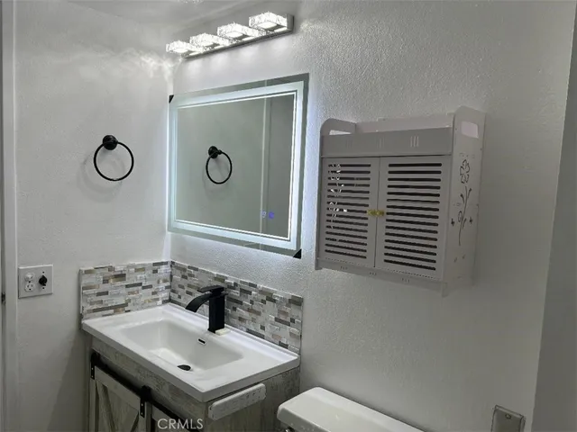 a bathroom with a sink a toilet and a mirror