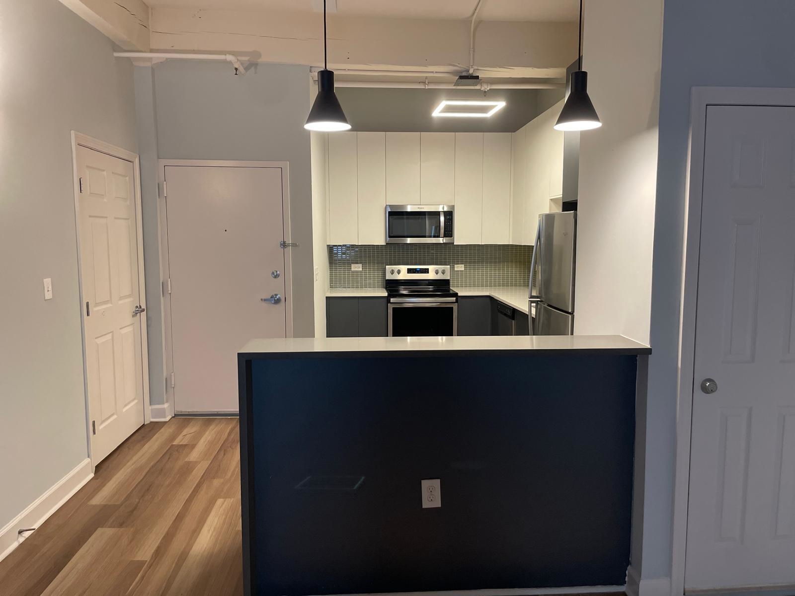 160 Lafayette Street, Unit 52306 Jersey City, NJ 07304 - Photo 7 of 25 a kitchen with kitchen island white cabinets and black appliances