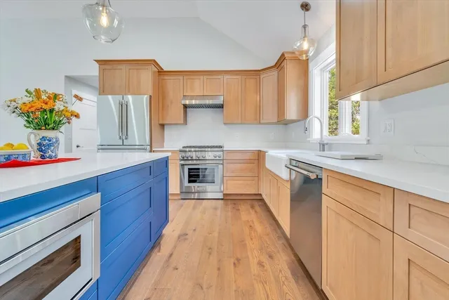 a kitchen with kitchen island granite countertop wooden floors stainless steel appliances a sink and cabinets