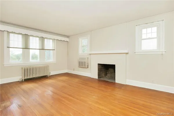 an empty room with windows and fireplace