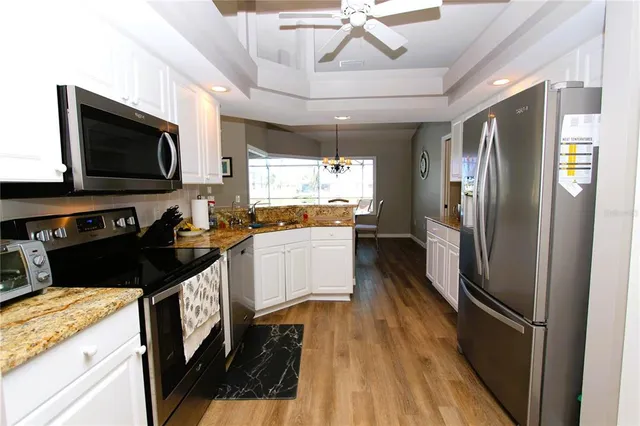 a kitchen with stainless steel appliances granite countertop a refrigerator a stove and a microwave