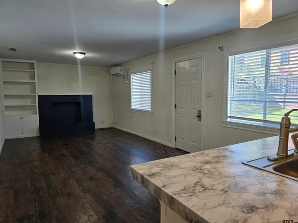a view of an empty room with window and wooden floor