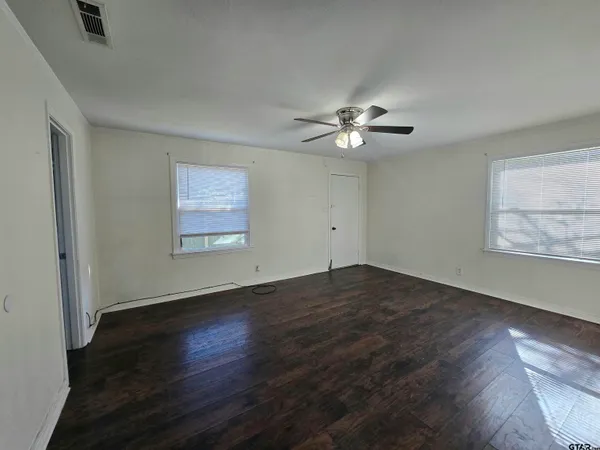 a view of an empty room with wooden floor and a window