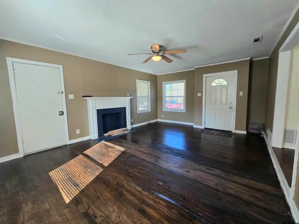 a view of an empty room with wooden floor fireplace and a window