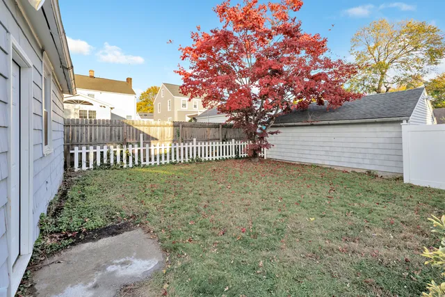 a view of a house with a small yard and a large tree