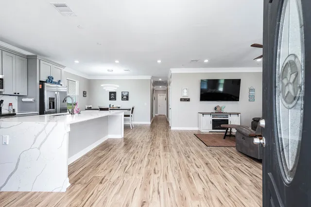 a kitchen with stainless steel appliances granite countertop a sink a stove a refrigerator cabinets and a dining table with wooden floor