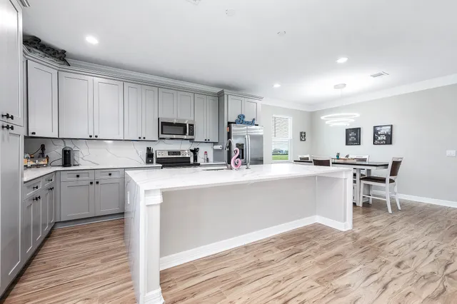 a kitchen with stainless steel appliances granite countertop a white table chairs and a refrigerator