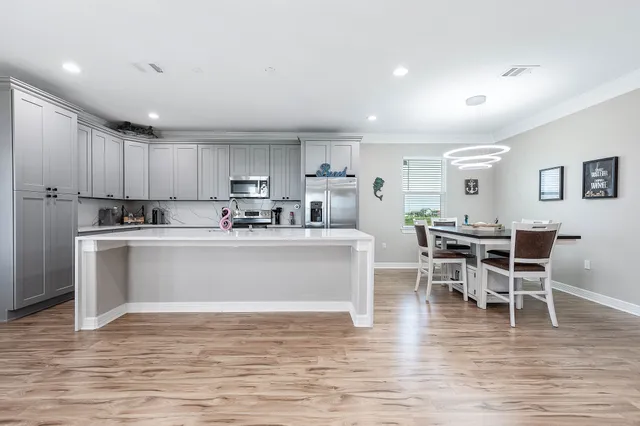 a kitchen with a dining table chairs and wooden floor
