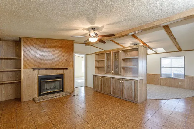 a view of an empty room with a fireplace and a ceiling fan