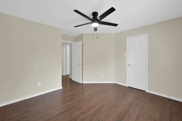 an empty room with wooden floor and ceiling fan