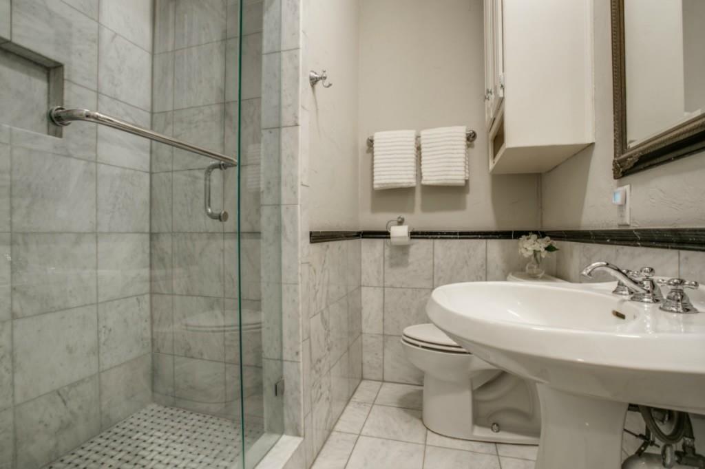 5419 Merrimac Avenue Dallas, TX 75206 - Photo 8 of 17 Bathroom featuring a glass-enclosed shower with tile surround, a pedestal sink with chrome fixtures, and a wall-mounted cabinet