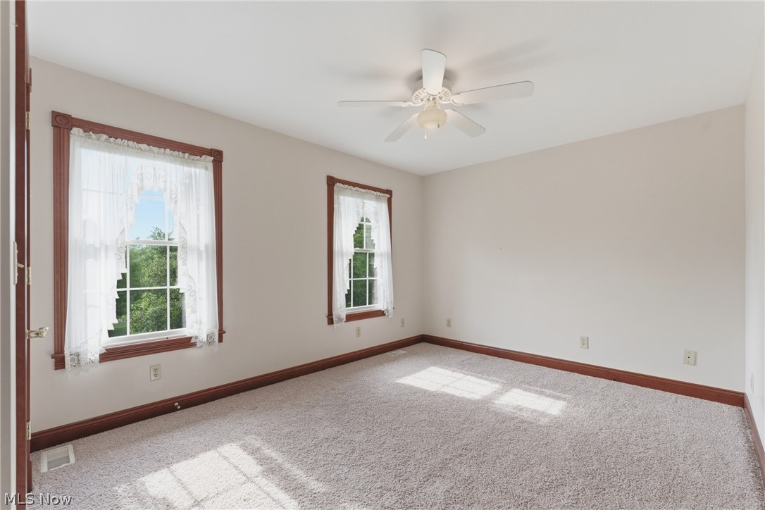 2184 Brenner Road Northeast Carrollton, OH 44615 - Photo 29 of 50 Carpeted interior space featuring two windows with white trim and a white ceiling fan