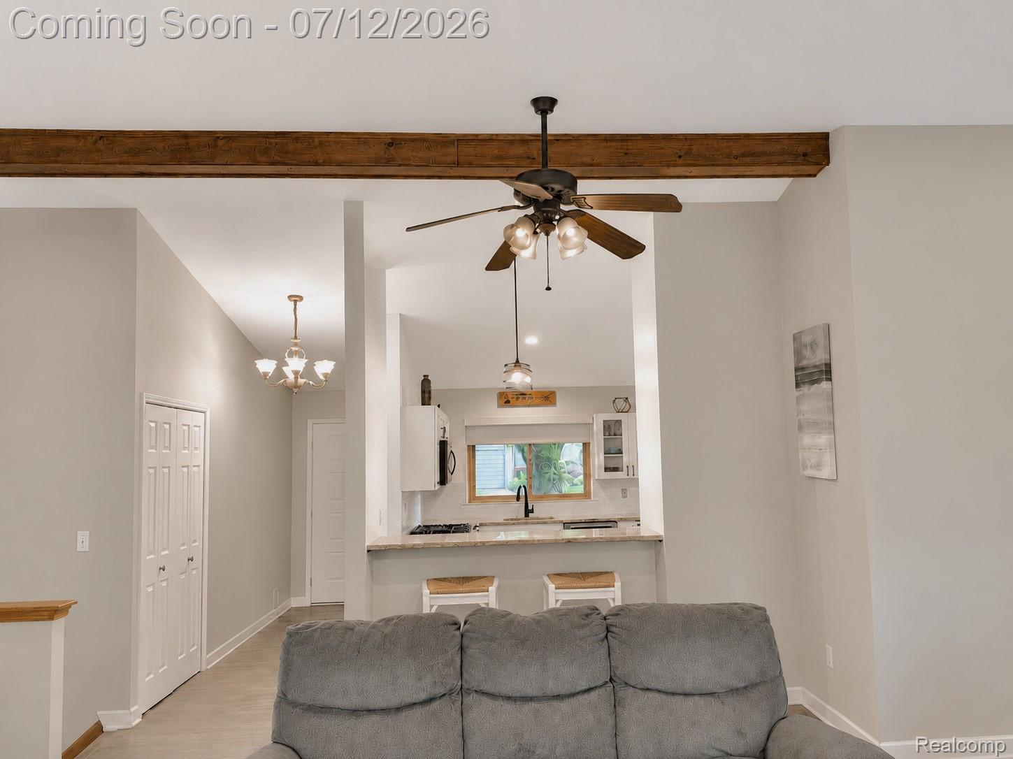 2033 Avonstoke Road Rochester, MI 48307 - Photo 6 of 26 Open concept living area with exposed beam details and a ceiling fan, offering a clear sightline to the kitchen featuring a breakfast bar with seating for two