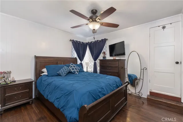 a bedroom with a bed and a dresser with wooden floor