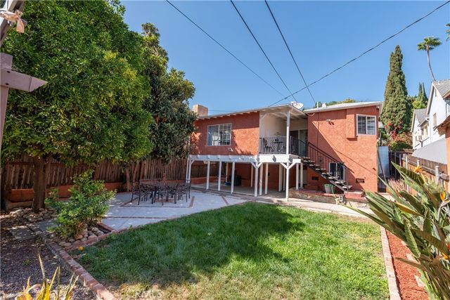 a view of a patio with table and chairs potted plants and large tree