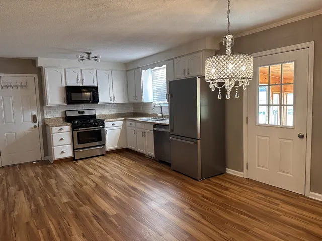 a kitchen with stainless steel appliances granite countertop a refrigerator a stove top oven a sink and dishwasher