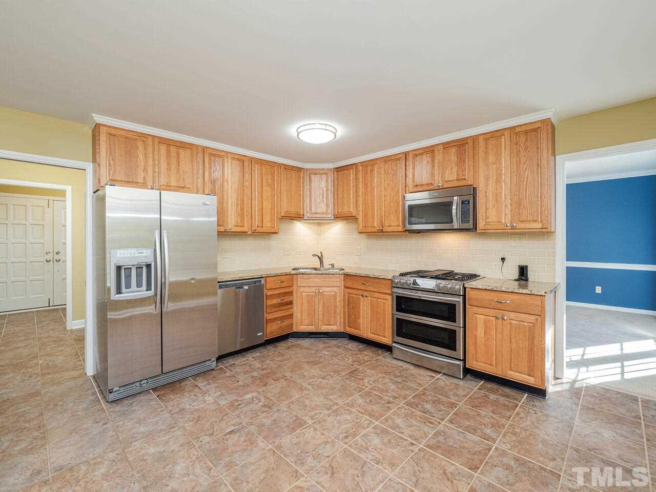 4604 Fernham Place Raleigh, NC 27612 - Photo 6 of 30 a kitchen with granite countertop a refrigerator and cabinets