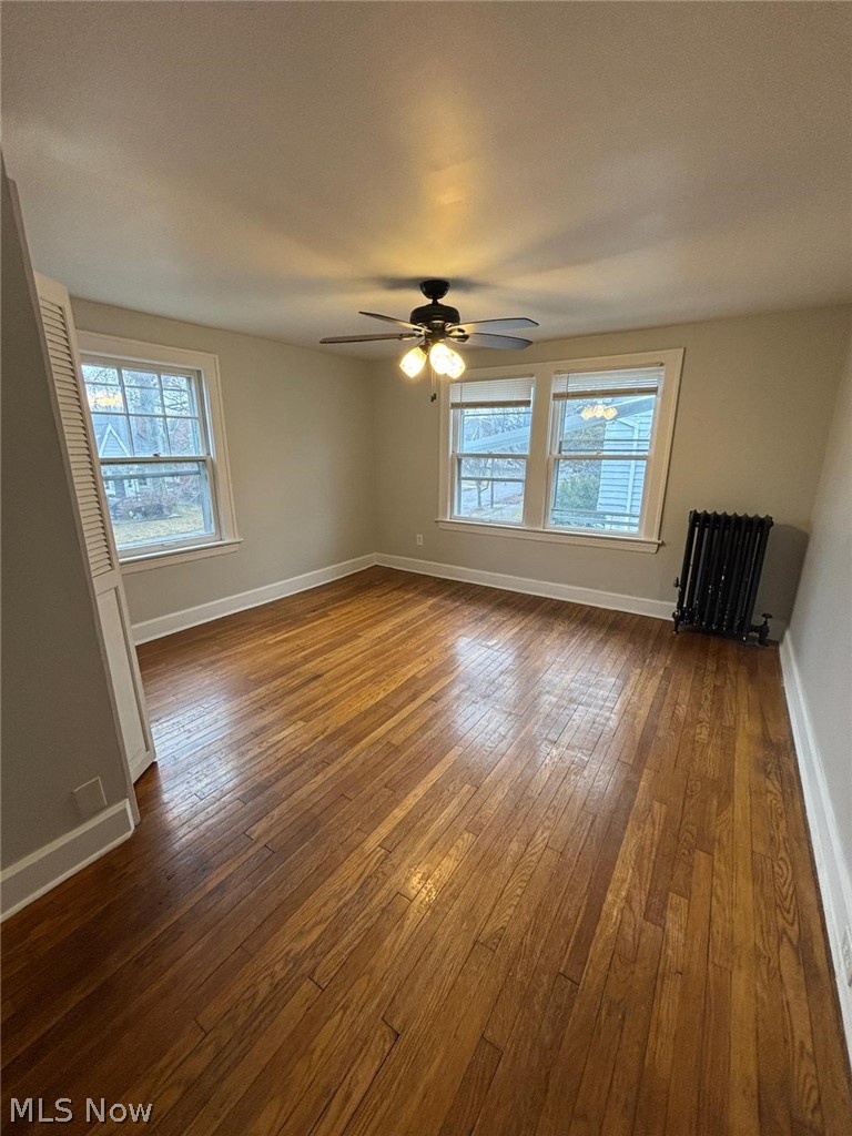 3808 Kirkwood Road Cleveland Heights, OH 44121 - Photo 4 of 6 Unfurnished room featuring dark wood-style flooring, radiator heating unit, and a ceiling fan