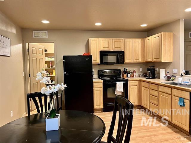 6498 South Lighthouse Place Boise, ID 83709 - Photo 2 of 16 Kitchen with light wood finish cabinetry, light countertops, black appliances, light wood finished floors, and recessed lighting