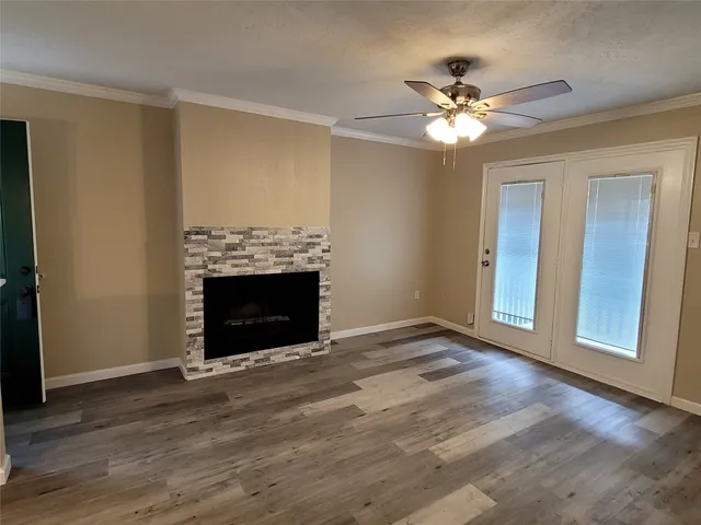 a view of an empty room with wooden floor fireplace and a window