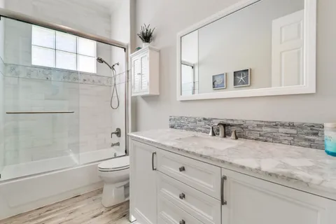 a bathroom with a granite countertop sink toilet and shower
