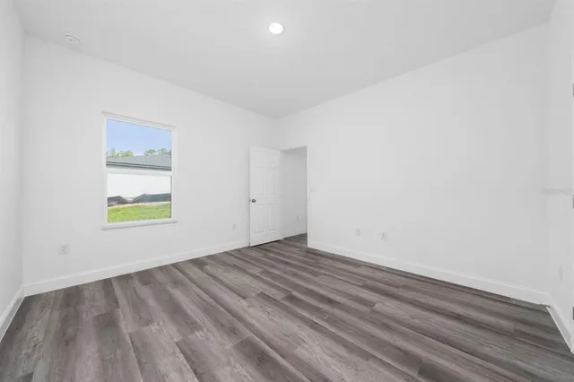 an empty room with wooden floor and window