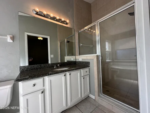a bathroom with a granite countertop sink a mirror and a shower