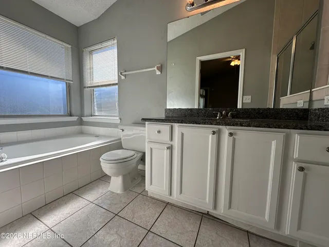 a bathroom with a granite countertop bathtub sink and toilet