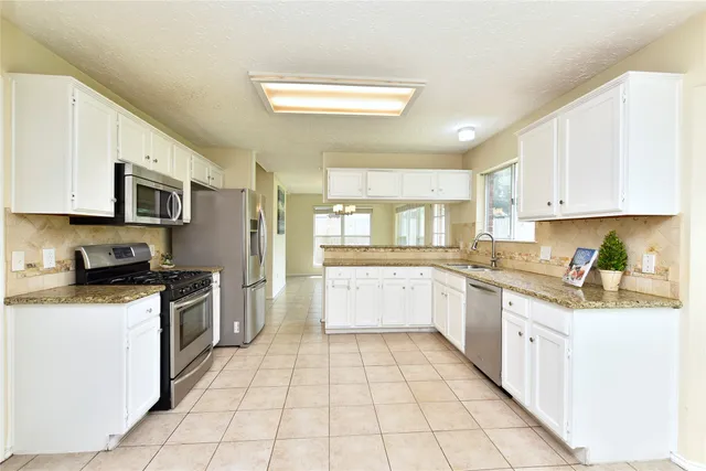 a large kitchen with a stove top oven a sink a counter space and cabinets