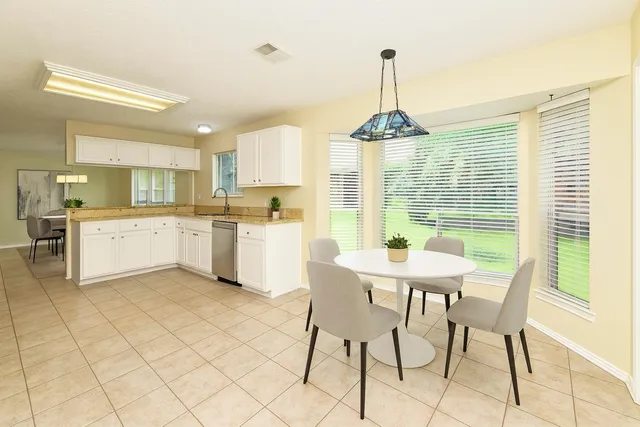a kitchen with stainless steel appliances kitchen island granite countertop a table chairs and a white cabinets