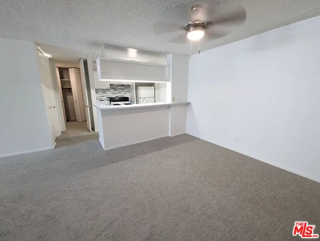 a view of a kitchen with a sink and dishwasher a refrigerator with white cabinets