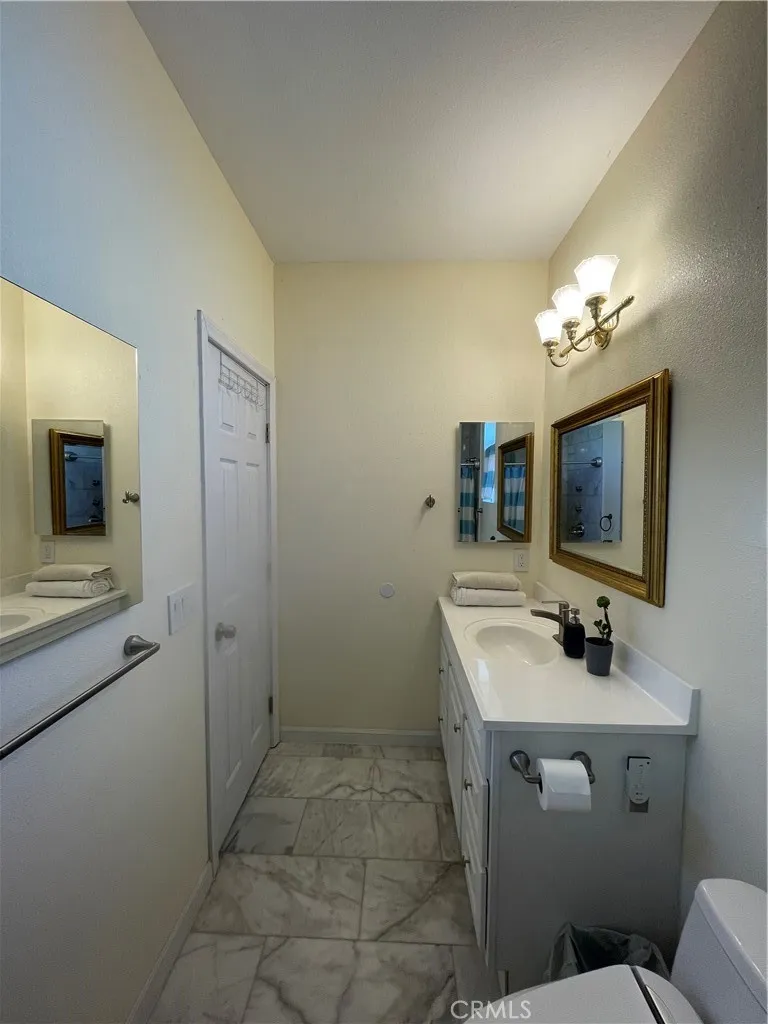 222 9th Street Huntington Beach, CA 92648 - Photo 2 of 13 a bathroom with a sink a toilet a mirror and shower