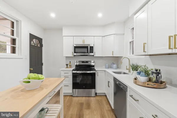 a kitchen with a sink white cabinets and appliances