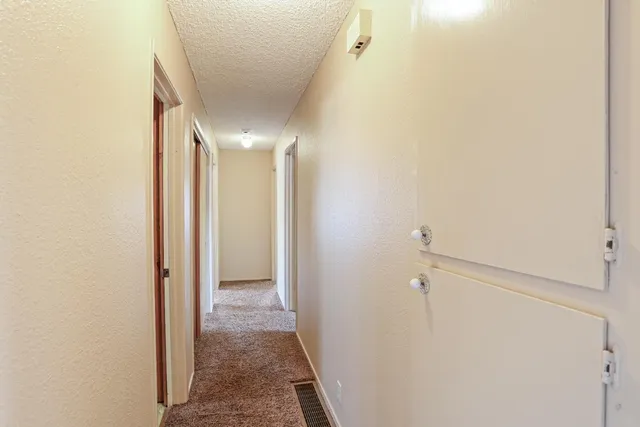 a view of a hallway with a chandelier fan and windows