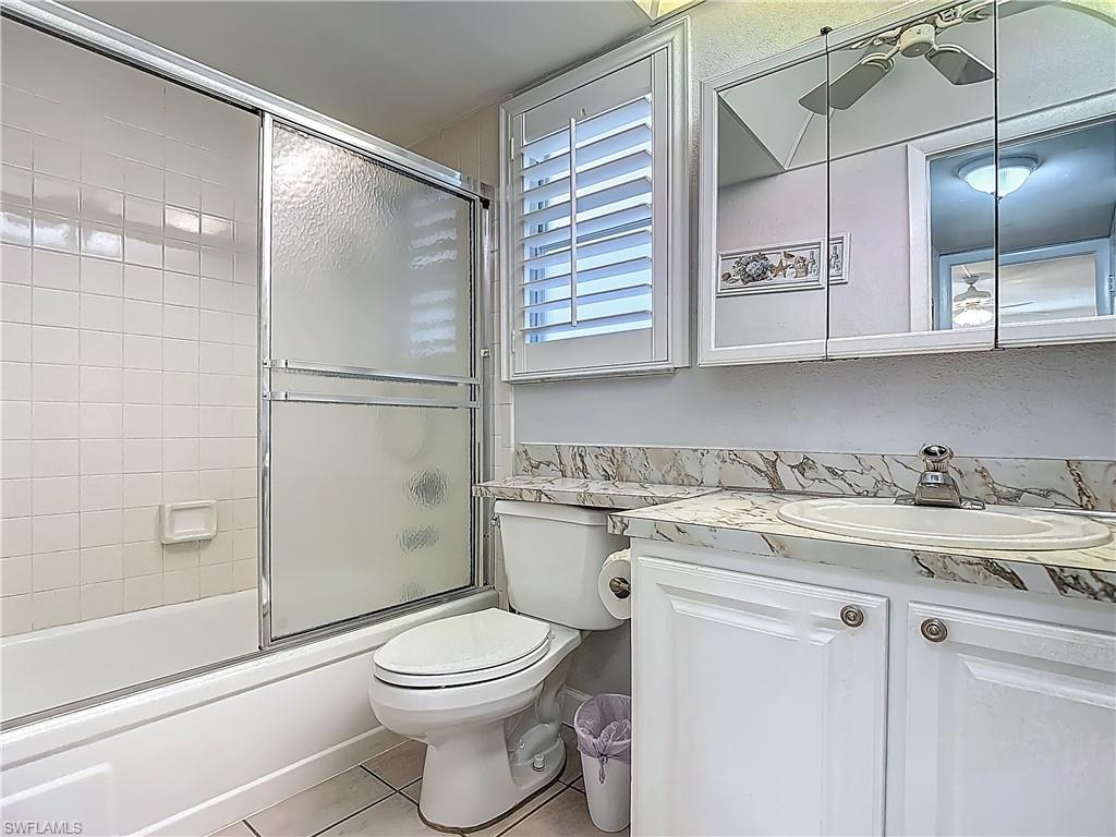 175 Turtle Lake Court, Unit 108 Naples, FL 34105 - Photo 13 of 17 Bathroom with vanity, tile patterned flooring, toilet, and enclosed tub / shower combo