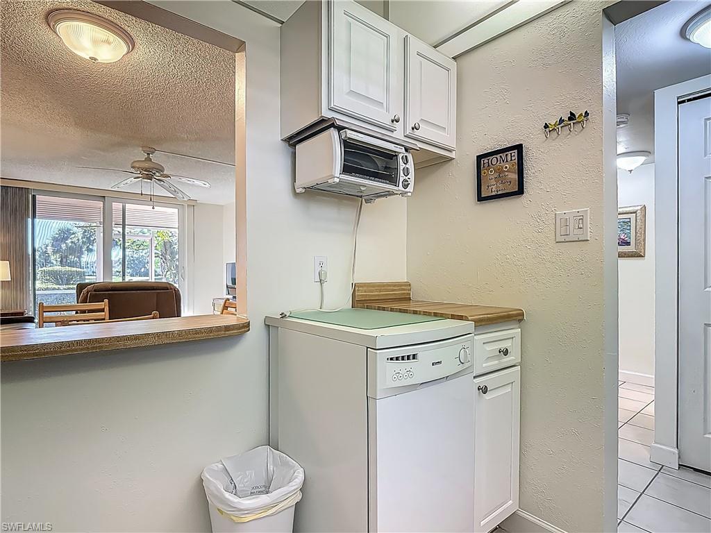 175 Turtle Lake Court, Unit 108 Naples, FL 34105 - Photo 5 of 17 Kitchen featuring fridge, ceiling fan, light tile patterned flooring, a textured ceiling, and white cabinetry