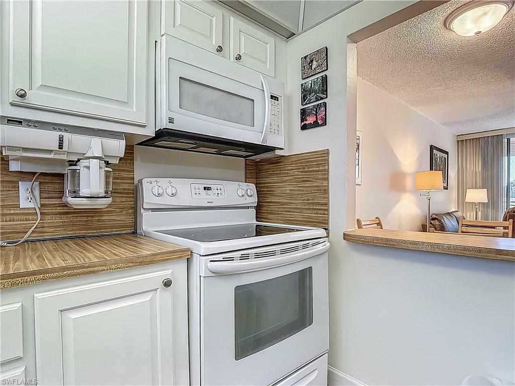 175 Turtle Lake Court, Unit 108 Naples, FL 34105 - Photo 6 of 17 Kitchen with white appliances, a textured ceiling, and decorative backsplash
