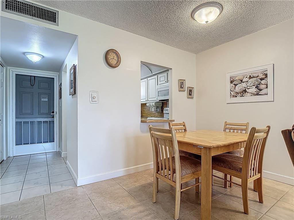 175 Turtle Lake Court, Unit 108 Naples, FL 34105 - Photo 8 of 17 Dining room featuring light tile patterned flooring, a textured ceiling, and baseboards