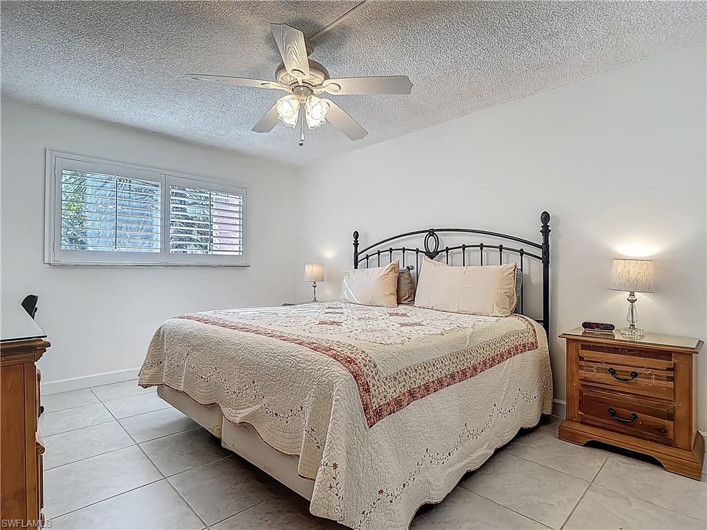 175 Turtle Lake Court, Unit 108 Naples, FL 34105 - Photo 10 of 17 Bedroom with light tile patterned flooring, a textured ceiling, ceiling fan, and baseboards